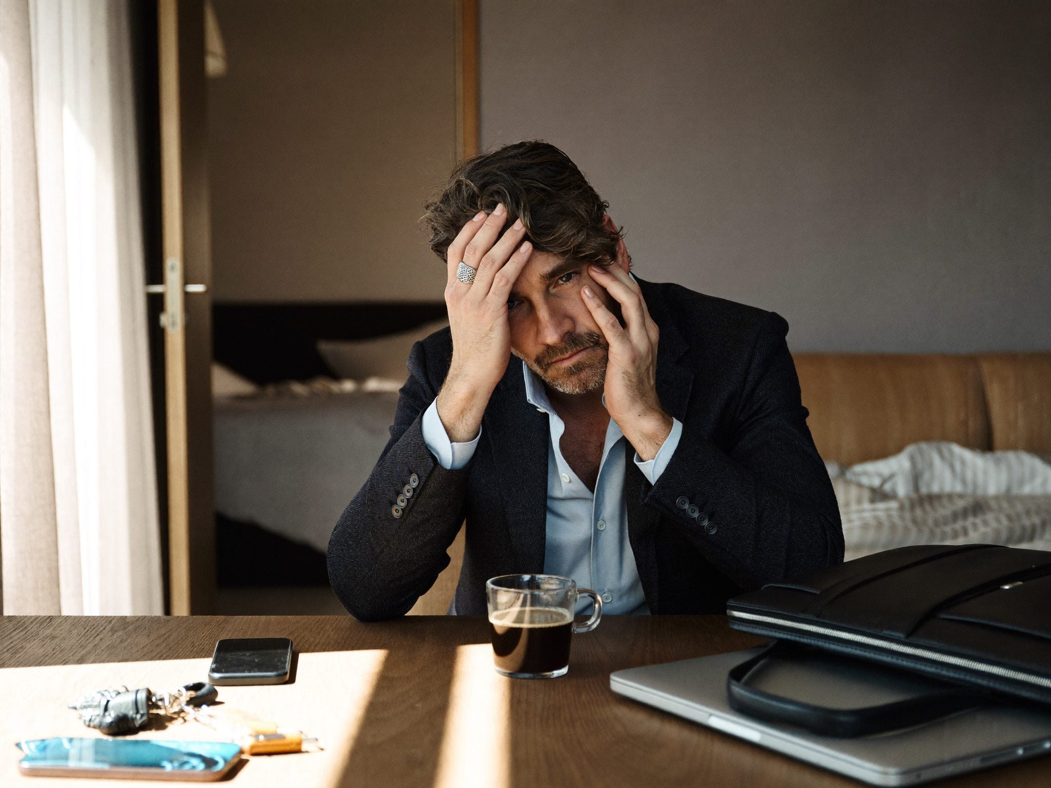 A tired working adult sitting at a desk with coffee nearby